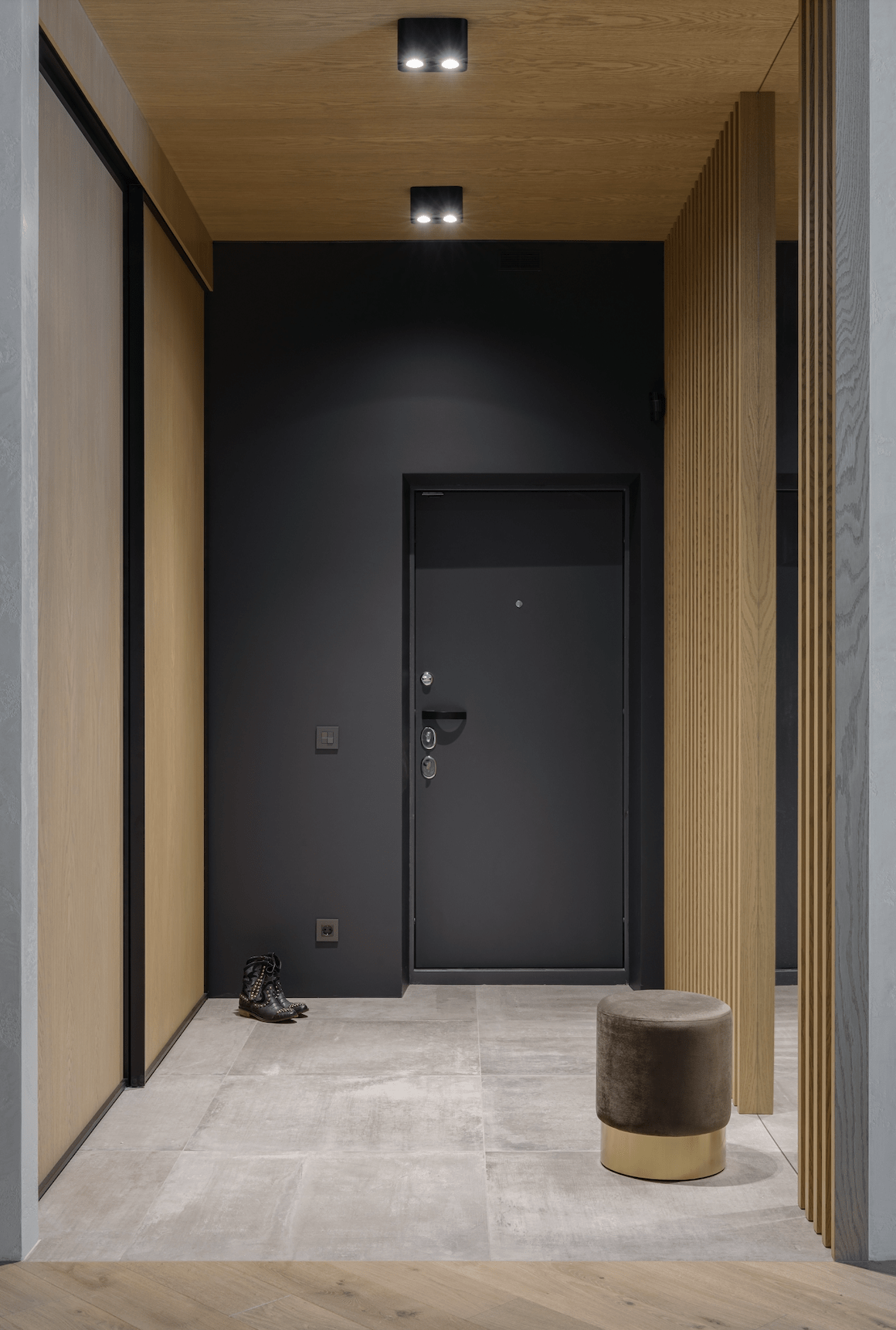 Flurbereich mit schwarzer Eingangstüre und Holzlamellenwänden